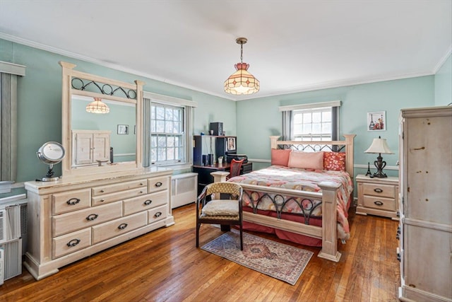 bedroom with dark wood-style floors, radiator, multiple windows, and ornamental molding