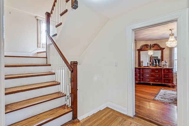 stairs with baseboards, a chandelier, and wood finished floors