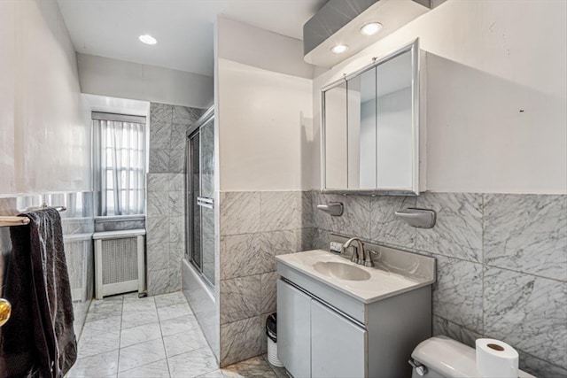 full bath with toilet, shower / bath combination with glass door, vanity, tile walls, and marble finish floor