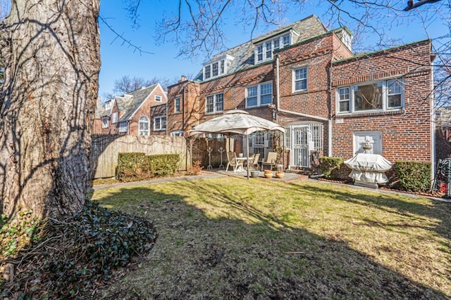 back of house featuring a yard, fence, brick siding, and a gazebo