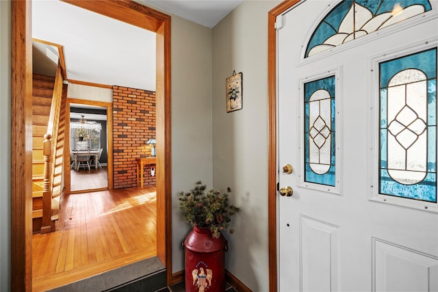 foyer with dark wood-style flooring and brick wall