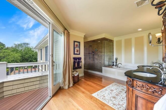 bathroom featuring hardwood / wood-style floors, ornamental molding, a bath, and vanity