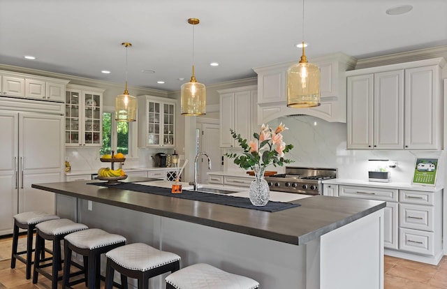 kitchen with range, a kitchen island with sink, and hanging light fixtures