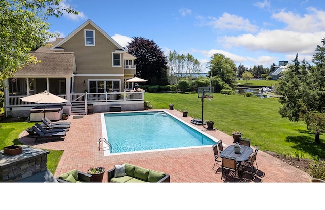 view of swimming pool featuring a deck with water view, a lawn, and a patio area