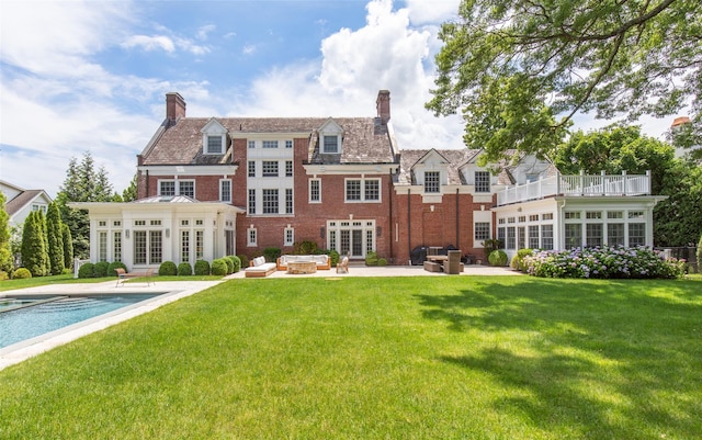 rear view of house featuring a patio, a lawn, a sunroom, and french doors