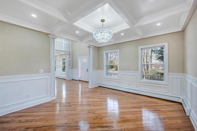 unfurnished dining area with decorative columns, a baseboard heating unit, an inviting chandelier, and beamed ceiling