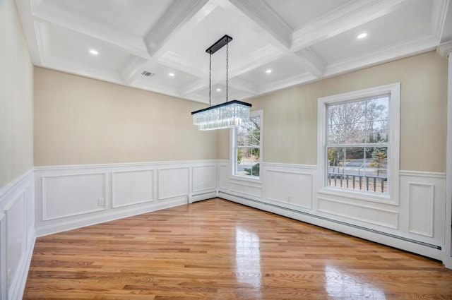 unfurnished dining area featuring light wood-type flooring, beam ceiling, coffered ceiling, a baseboard heating unit, and an inviting chandelier