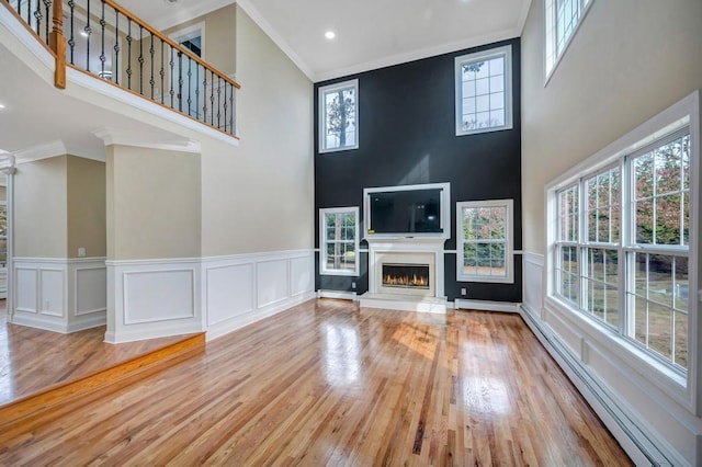 unfurnished living room with baseboard heating, plenty of natural light, and light hardwood / wood-style floors