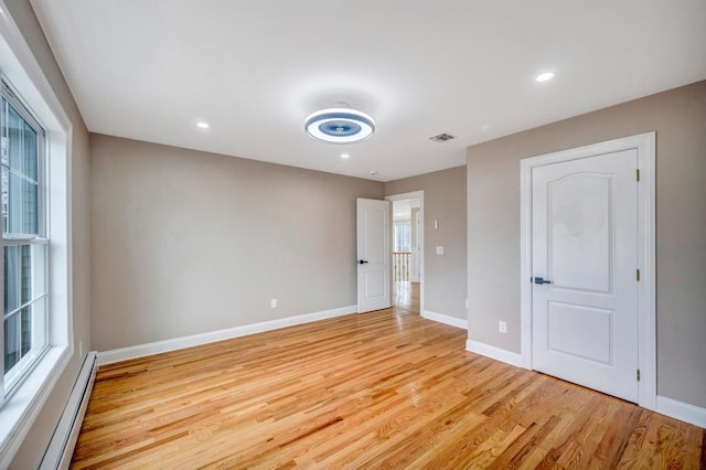 empty room with a baseboard radiator and light hardwood / wood-style flooring