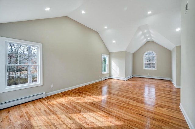 unfurnished living room featuring vaulted ceiling, a baseboard heating unit, and light wood-type flooring