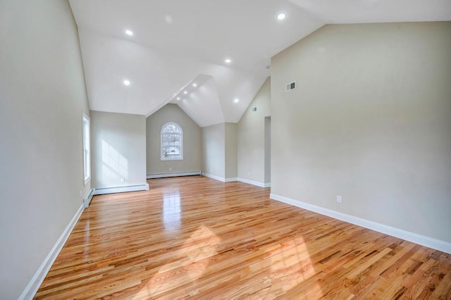 additional living space featuring lofted ceiling, baseboard heating, and light hardwood / wood-style flooring