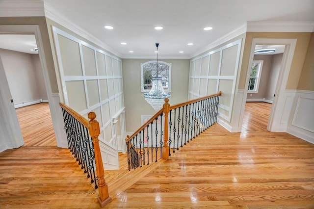 corridor featuring an inviting chandelier, crown molding, light wood-type flooring, and baseboard heating