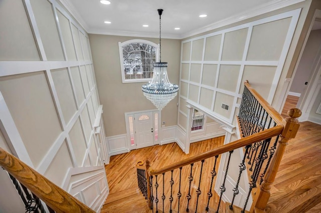 staircase with ornamental molding, a chandelier, and hardwood / wood-style floors