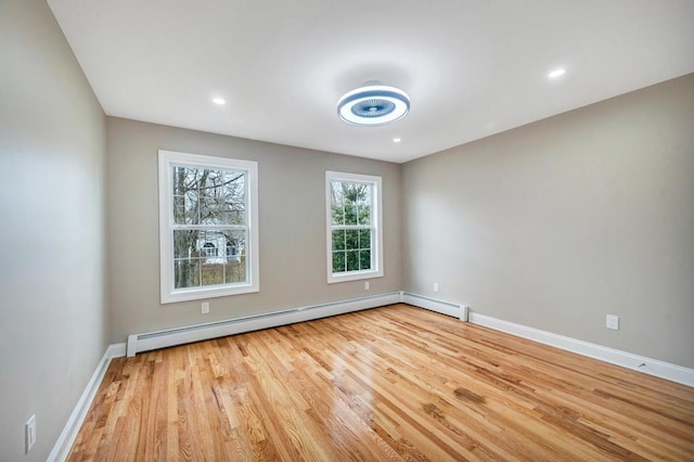 empty room featuring a baseboard heating unit and light hardwood / wood-style floors