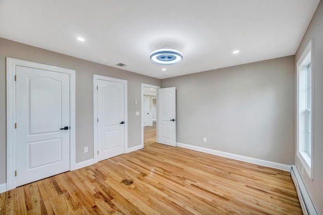 unfurnished bedroom featuring a baseboard radiator and light hardwood / wood-style floors