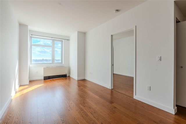 spare room featuring radiator and hardwood / wood-style flooring