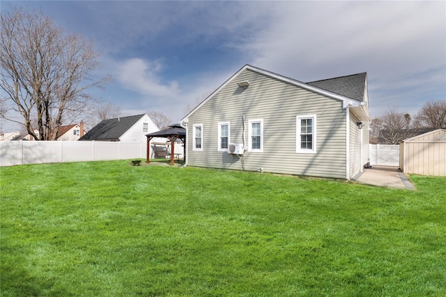 back of house featuring fence, a gazebo, and a lawn