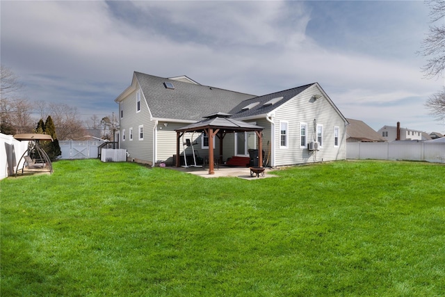 rear view of house featuring a shingled roof, a fenced backyard, a gazebo, a yard, and a patio area