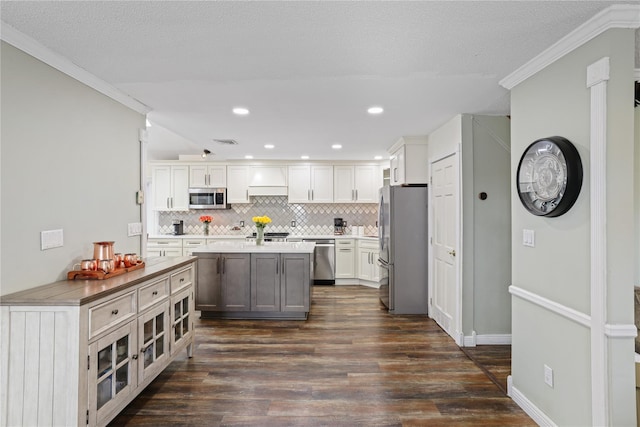 kitchen featuring white cabinets, decorative backsplash, dark wood-style floors, stainless steel appliances, and light countertops