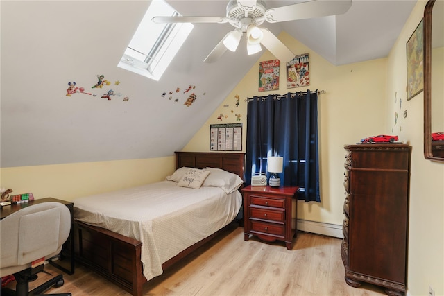 bedroom with vaulted ceiling with skylight, light wood-style flooring, a baseboard heating unit, and a ceiling fan