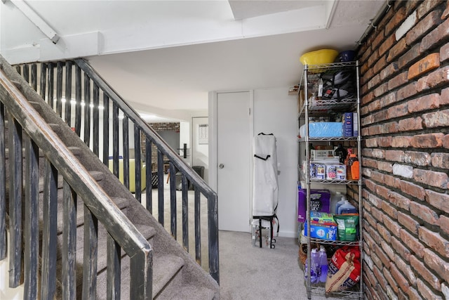 staircase featuring carpet floors and brick wall