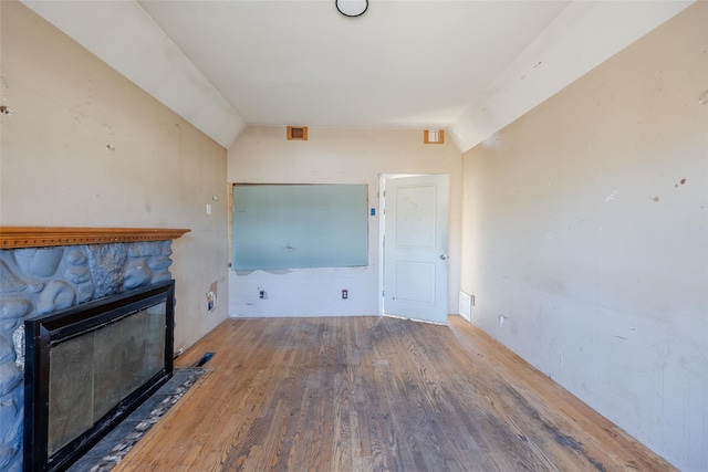 unfurnished living room featuring lofted ceiling, a fireplace, and wood-type flooring