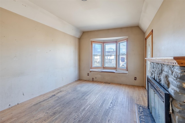 unfurnished living room featuring vaulted ceiling and light hardwood / wood-style floors