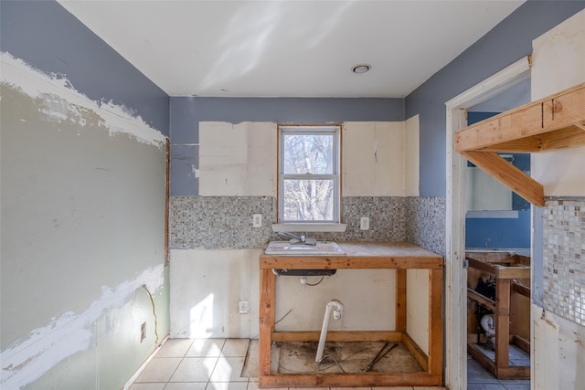 kitchen featuring tile countertops, sink, light tile patterned floors, and backsplash