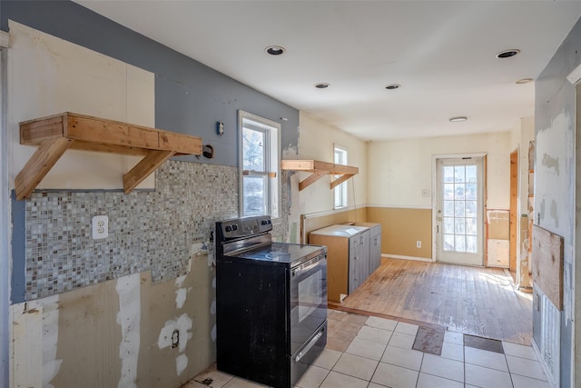 kitchen featuring tasteful backsplash, black range with electric stovetop, plenty of natural light, and light tile patterned flooring