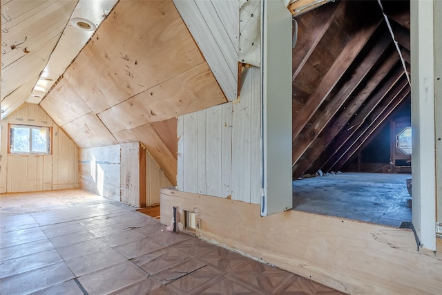 bonus room featuring lofted ceiling and wooden walls