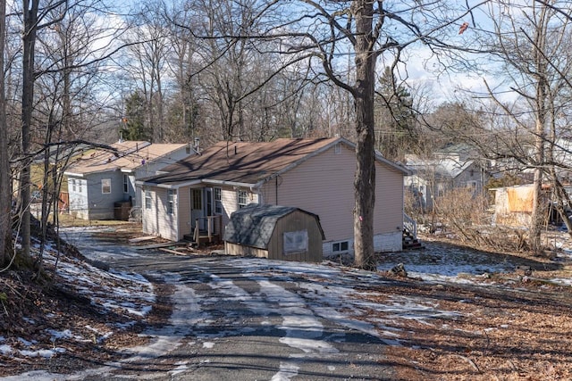 view of property exterior with a shed, an outdoor structure, and aphalt driveway