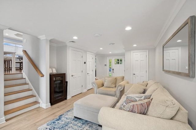 living area featuring stairs, ornamental molding, a healthy amount of sunlight, and light wood-style floors