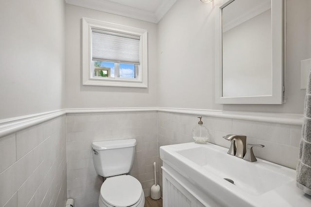 half bath with a wainscoted wall, a sink, and toilet