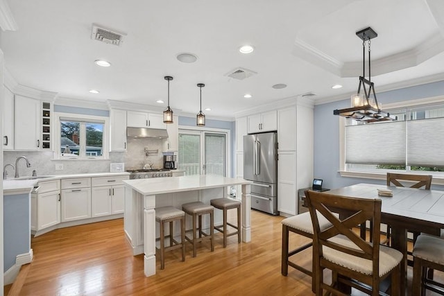 kitchen with decorative light fixtures, visible vents, light countertops, a kitchen island, and high quality fridge