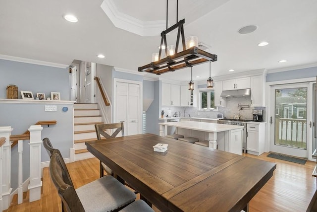 dining room featuring light wood-style floors, stairs, and crown molding