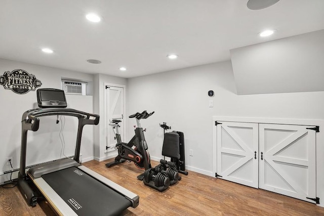 workout area with baseboards, a wall mounted air conditioner, wood finished floors, and recessed lighting