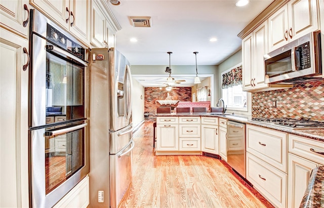 8 Lucky Ln, Washingtonville, NY 10992 - kitchen with appliances with stainless steel finishes, cream cabinetry, a sink, light wood finished floors, and a peninsula