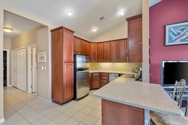 kitchen with stainless steel appliances, a peninsula, visible vents, light countertops, and a kitchen bar