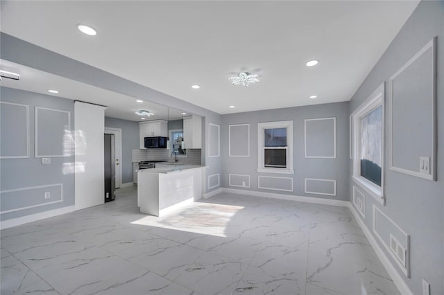 kitchen with white cabinetry, sink, backsplash, and kitchen peninsula