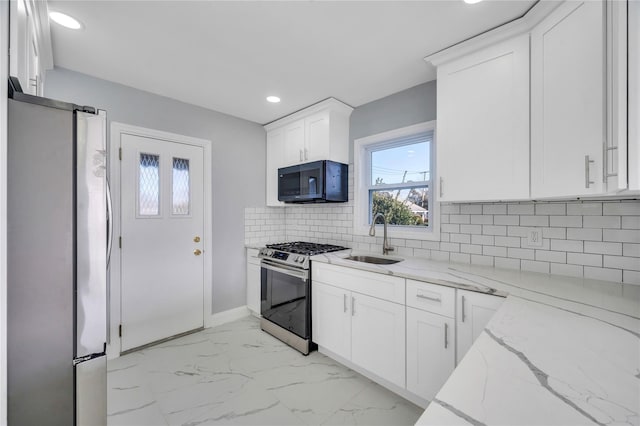 kitchen with sink, stainless steel appliances, light stone countertops, decorative backsplash, and white cabinets