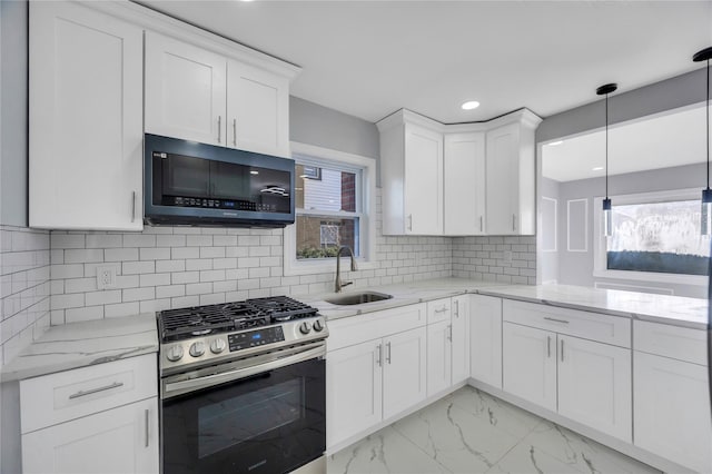 kitchen featuring decorative light fixtures, white cabinetry, sink, stainless steel gas range oven, and light stone countertops