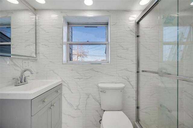 bathroom with vanity, a shower with shower door, tile walls, and toilet