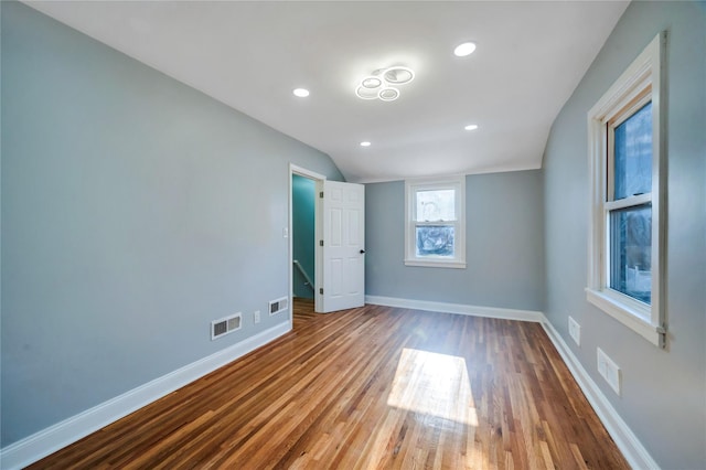 unfurnished bedroom featuring hardwood / wood-style flooring and vaulted ceiling