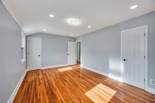 unfurnished bedroom with lofted ceiling and light hardwood / wood-style floors