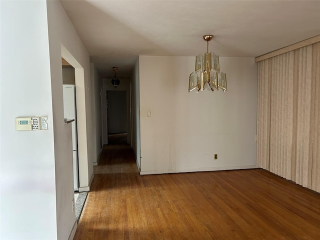 unfurnished dining area featuring an inviting chandelier and hardwood / wood-style floors