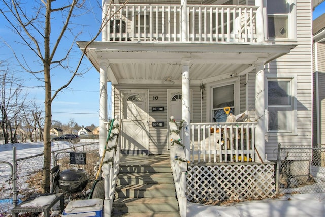 property entrance featuring covered porch and fence