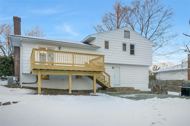 snow covered house with a wooden deck and central air condition unit