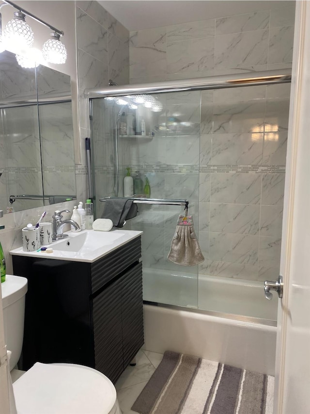 full bathroom with vanity, tile walls, toilet, and combined bath / shower with glass door