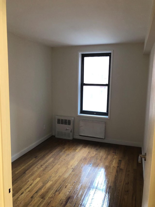 spare room with radiator and dark hardwood / wood-style flooring