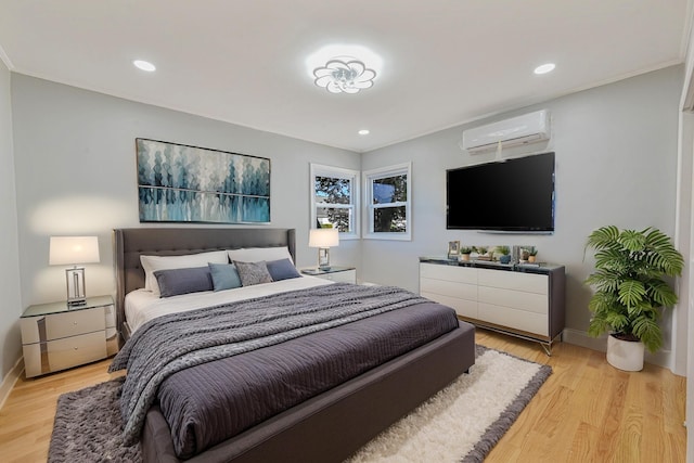 bedroom with a wall mounted air conditioner and light hardwood / wood-style flooring